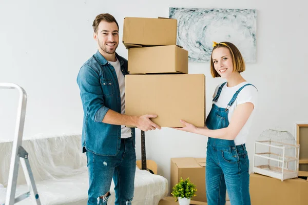 Happy couple holding cardboard boxes and looking at camera — Stock Photo