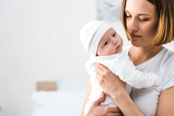 Giovane madre in t-shirt bianca che tiene il bambino a casa — Foto stock