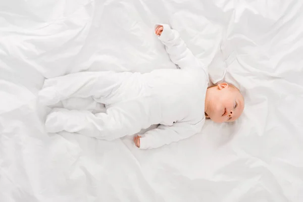 Вид сверху младенца, лежащего на белой простыне — стоковое фото
