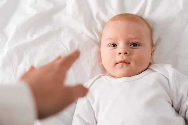 Cropped view of mother and baby lying on white sheet — Stock Photo