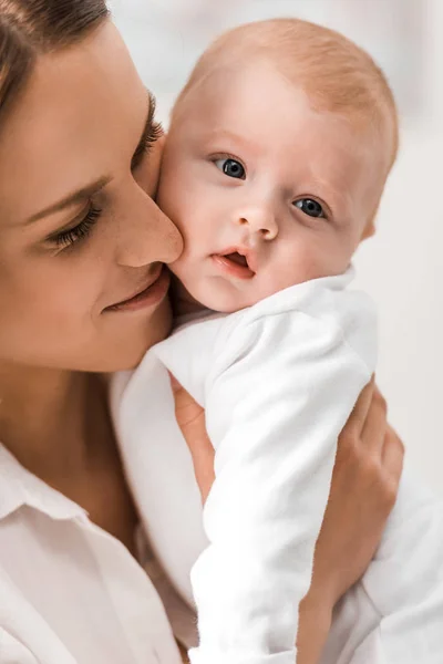 Mother in white shirt holding baby at home — Stock Photo