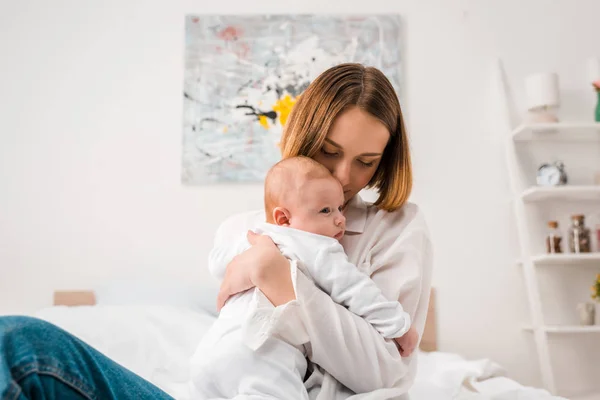 Happy mother in white shirt holding baby at home — Stock Photo