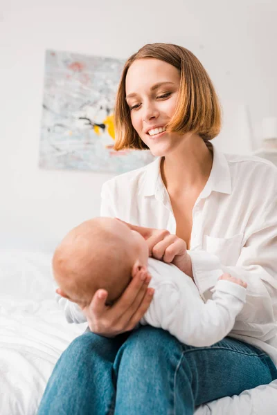 Mãe feliz em camisa branca segurando bebê em casa — Fotografia de Stock