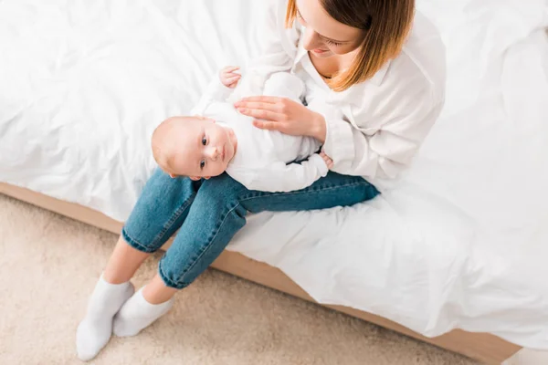 Visão aérea de molther jovem brincando com o bebê na cama — Fotografia de Stock