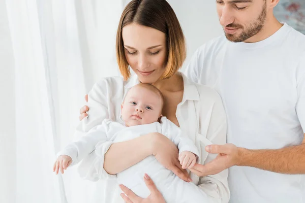 Vista recortada de la familia feliz con el bebé en casa - foto de stock