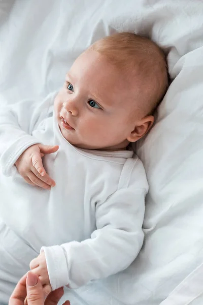Cropped view of mother holding hands with baby on bed — Stock Photo