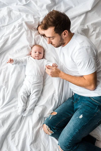 Vista superior del bebé y el padre acostado en la cama - foto de stock