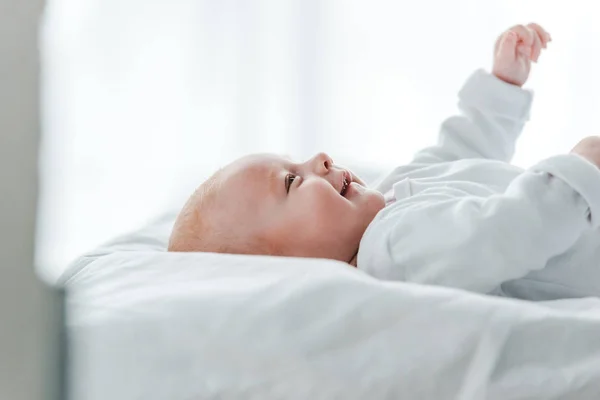 Смеющийся милый ребенок лежит на кровати дома — стоковое фото