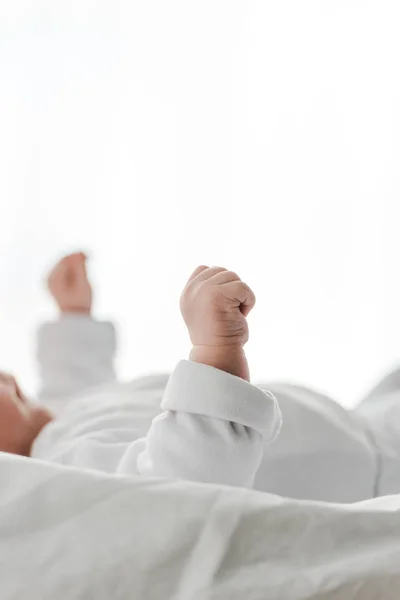Обрезанный вид ребенка в белой одежде лежал на кровати — стоковое фото