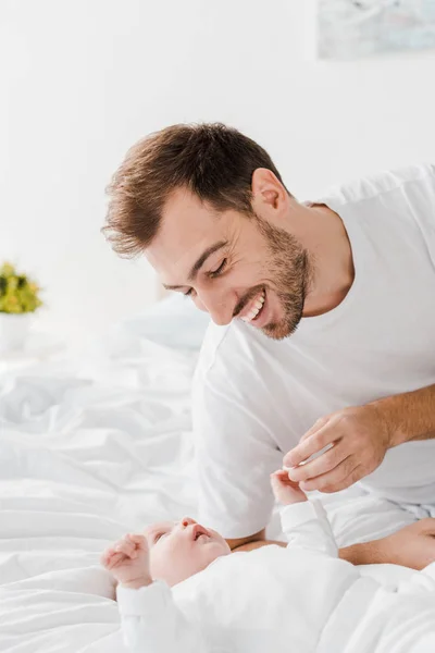 Glücklicher junger Vater liegt mit Baby im Bett — Stockfoto