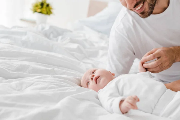 Ausgeschnittener Blick auf glücklichen jungen Vater, der mit Baby im Bett liegt — Stockfoto