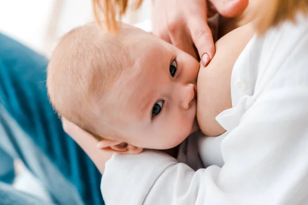 Частичный взгляд женщины, кормящей грудью ребенка дома — стоковое фото