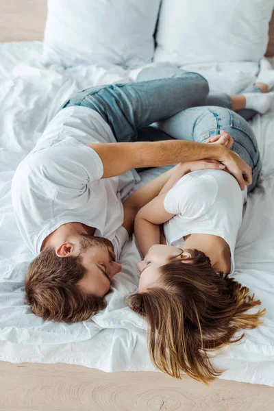 Blick von oben auf Paar in Jeans, das sich auf dem Bett umarmt — Stockfoto