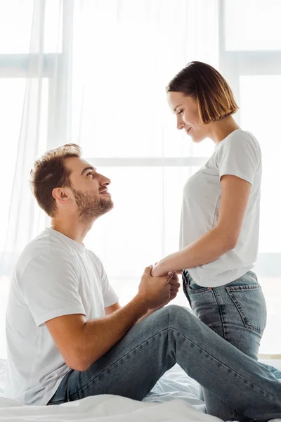 Счастливые пары держатся за руки и смотрят друг на друга в спальне — стоковое фото