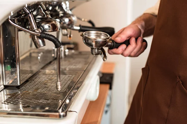 Partial view of barista holding portafilter near coffee machine — Stock Photo