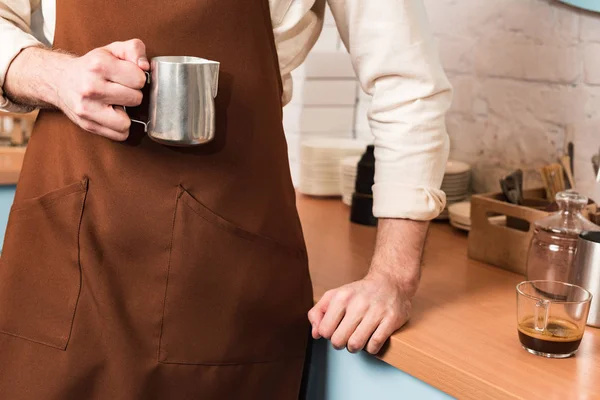Cropped view of barista holding steel milk jug — Stock Photo