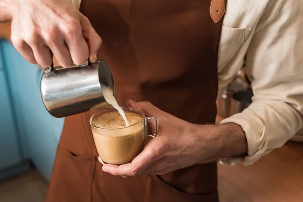 Vue recadrée du barista versant du lait dans le café — Photo de stock