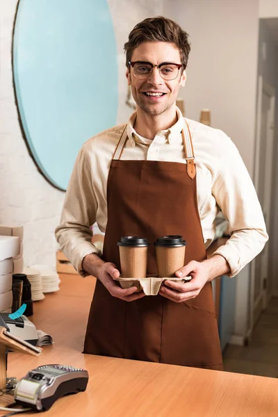 Усміхнений бариста в окулярах тримає чашку з чашкою кави — стокове фото