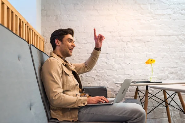 Freelancer che lavora con computer portatile e mostra il segno di idea in caffè — Foto stock