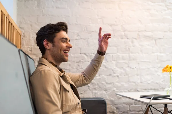 Joven sonriente mostrando signo de idea en la cafetería - foto de stock