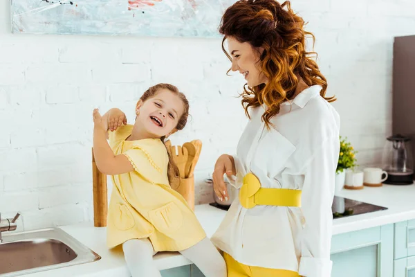 Felice madre ridendo con carina figlia insieme in cucina — Foto stock