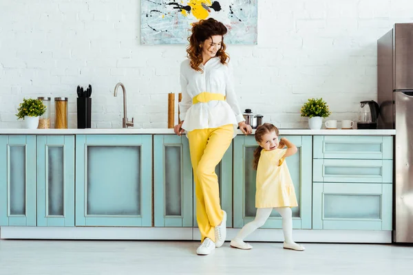 Mãe feliz de pé com filha emocional na cozinha — Fotografia de Stock