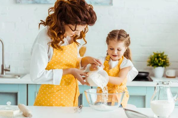 Mère aidant fille ajoutant de la farine au bol dans la cuisine — Photo de stock