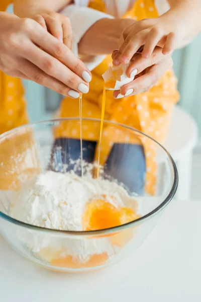 Zugeschnittene Ansicht von Mutter und Tochter, die Ei in Schüssel mit Mehl zertrümmern — Stockfoto