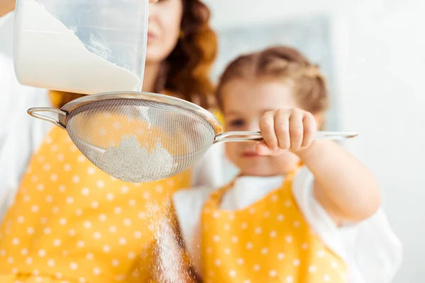 Messa a fuoco selettiva di madre e figlia setacciando la farina insieme — Foto stock