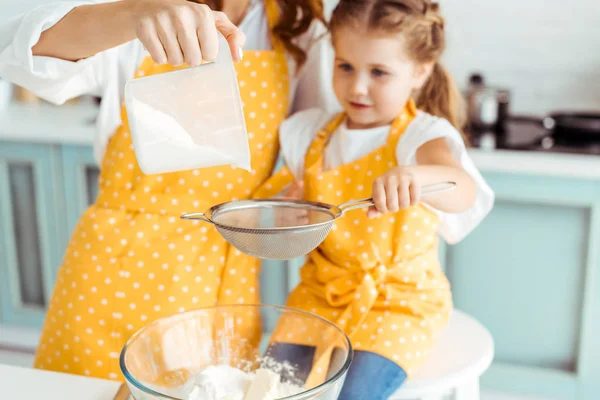 Selective focus of mother and daughter sieving flour together into bowl — Stock Photo