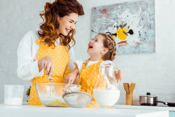Happy mother with excited daughter cooking dough together in kitchen — Stock Photo