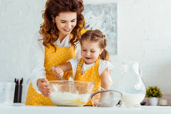 Glückliche Mutter und Tochter kochen gemeinsam Teig am Tisch in der Küche — Stockfoto