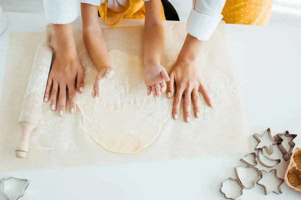 Vue du dessus de la mère et de la fille avec pâte, rouleau à pâtisserie et moules à pâte sur la table — Photo de stock