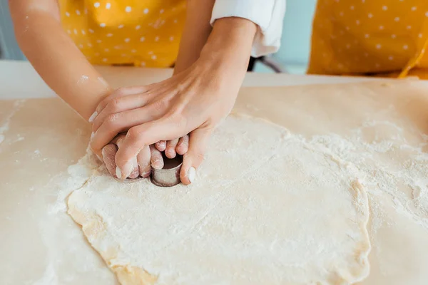 Cropped view of mother and daughter using dough molds on dough — Stock Photo