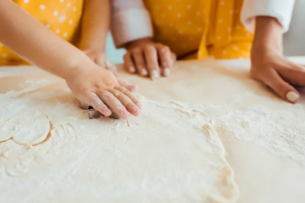 Partial view of daughter using heart shaped dough mold — Stock Photo