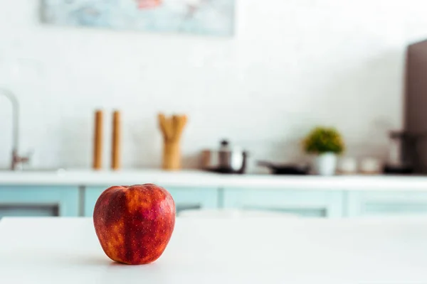 Красное свежее яблоко на белом кухонном столе — стоковое фото