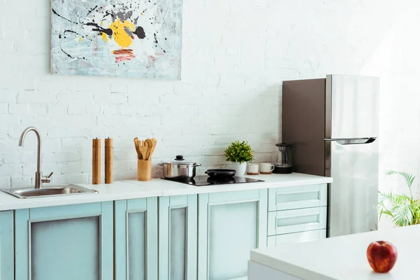 Cozinha leve espaçosa com utensílios de cozinha e maçã vermelha na mesa — Fotografia de Stock