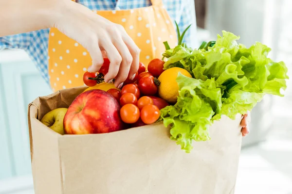 Vue recadrée d'une femme touchant des fruits et légumes frais mûrs dans un sac en papier — Photo de stock