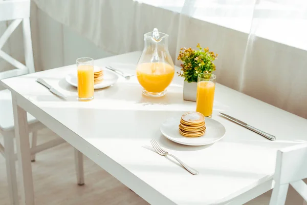 Sweet pancakes with fresh orange juice served for breakfast on white table — Stock Photo