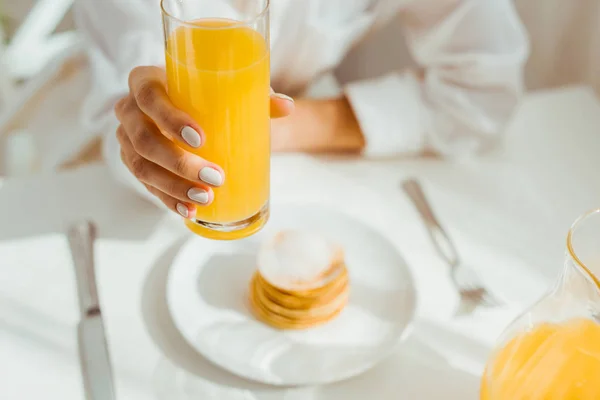 Enfoque selectivo de la mujer sosteniendo vidrio con jugo de naranja - foto de stock