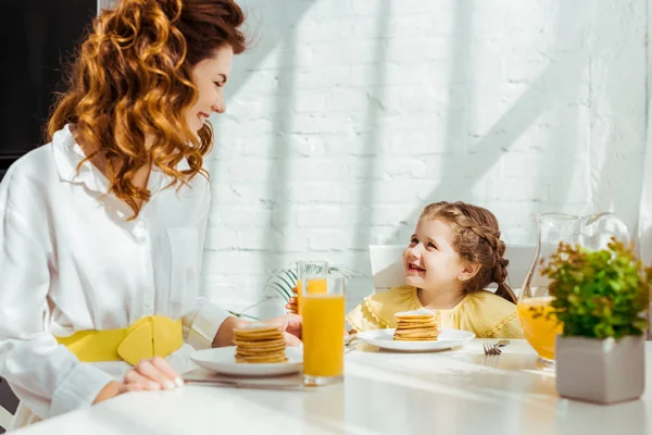 Bonito criança olhando feliz mãe enquanto tomando café da manhã juntos — Fotografia de Stock