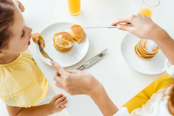 Vue aérienne de la mère nourrissant sa fille avec des crêpes — Photo de stock