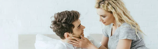 Panoramic shot of blonde woman looking and touching face of handsome man — Stock Photo