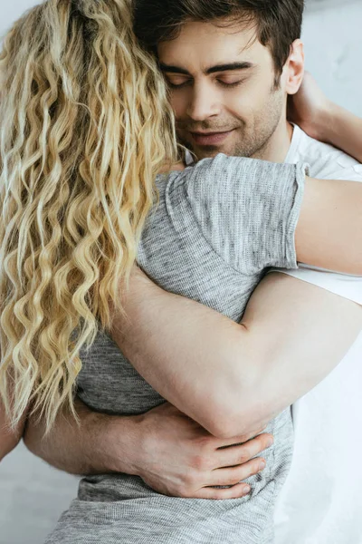 Вид сзади блондинки, обнимающейся со счастливым парнем с закрытыми глазами — стоковое фото