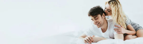 Tiro panorâmico de menina loira feliz abraçando namorado bonito deitado na cama — Fotografia de Stock