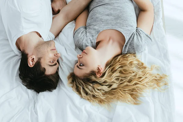 Vista superior da jovem loira deitada na cama com o homem feliz — Fotografia de Stock