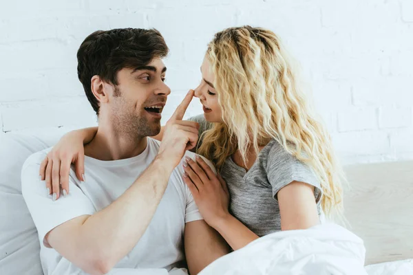 Cheerful man touching nose of attractive blonde girlfriend — Stock Photo