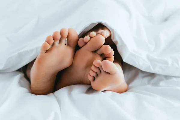 Vista ritagliata di fidanzata e fidanzato a piedi nudi sdraiato a letto — Foto stock