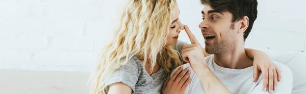 Panoramic shot of cheerful man touching nose of attractive blonde girlfriend — Stock Photo