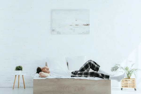 Щасливий і красивий чоловік лежить на ліжку в сучасній спальні — стокове фото